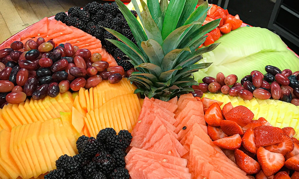 A plate of grapes, pineapple, and melon